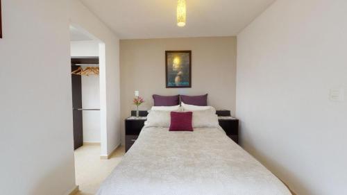 a bedroom with a large white bed with purple pillows at Casa muy acogedora con excelente ubicación, cerca Centro dinámico Pegaso, Parques industriales, Aeropuerto Toluca in Toluca