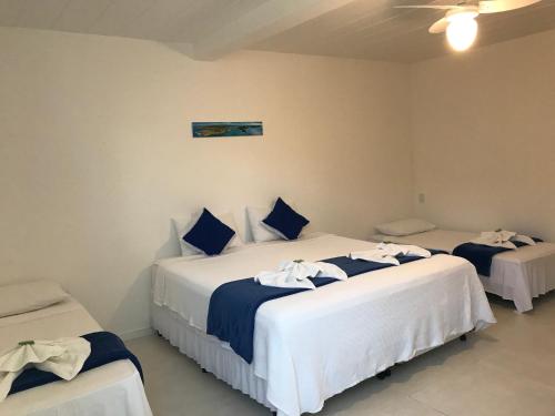 a bedroom with three beds with blue and white sheets at Guest House Forno in Búzios