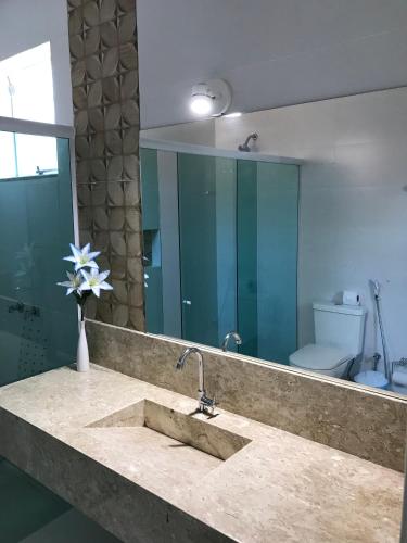 a bathroom with a sink with a mirror and a toilet at Guest House Forno in Búzios