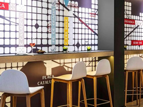 a bar with three stools in front of a counter at ibis Styles Barcelona Centre in Barcelona
