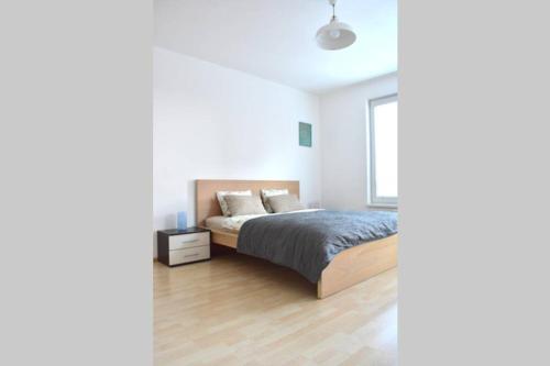 a white bedroom with a bed and a window at Modern apartments - Airport 8mins in Prague