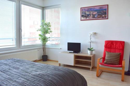 a bedroom with a bed and a tv and a chair at Modern apartments - Airport 8mins in Prague