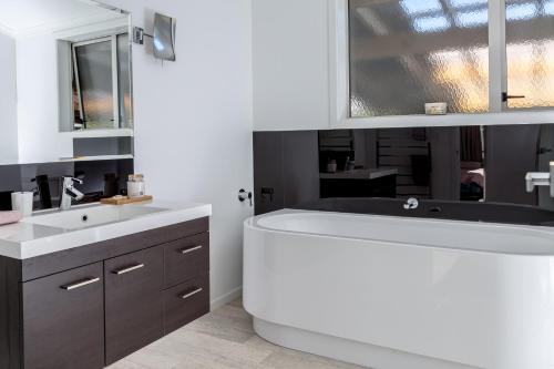 ein Badezimmer mit einer weißen Badewanne und einem Waschbecken in der Unterkunft Casa Toscana in Martinborough 