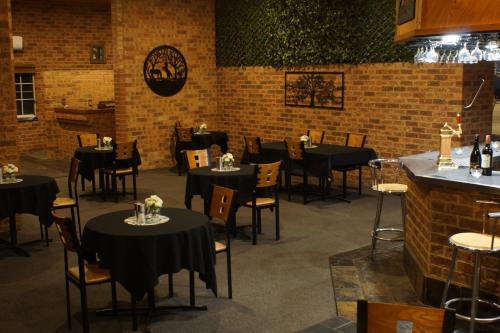 a dining room with black tables and chairs and a brick wall at Colonial Motor Inn in West Wyalong