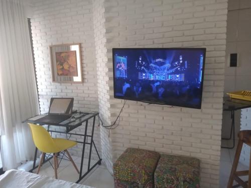 uma sala de estar com televisão numa parede de tijolos em Flat Ana Regis ap1010 em Salvador