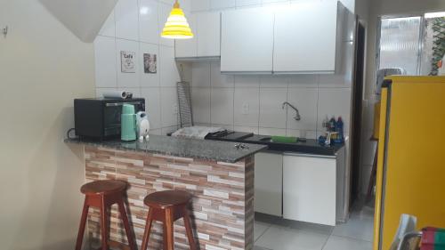 une cuisine avec un comptoir avec des tabourets et un four micro-ondes dans l'établissement Salinópolis Praia, à Salinópolis