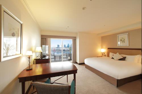 a hotel room with a bed and a desk and a window at Kobe Meriken Park Oriental Hotel in Kobe