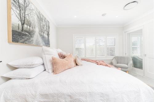 a white bedroom with a large white bed with pillows at Hall House in Bowral