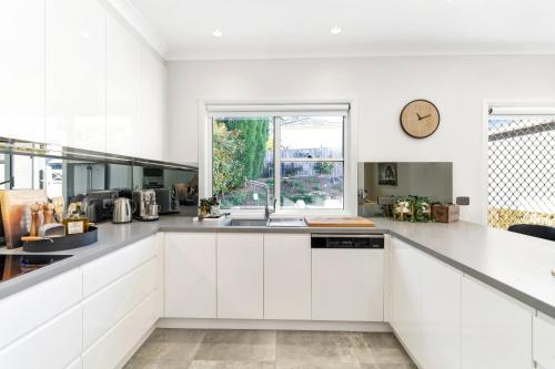 a white kitchen with a sink and a window at Hall House in Bowral