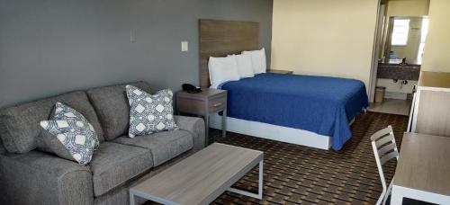 a hotel room with a couch and a bed at Ameristay Inn & Suites in Orange