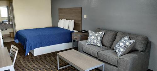 a hotel room with a couch and a bed at Ameristay Inn & Suites in Orange