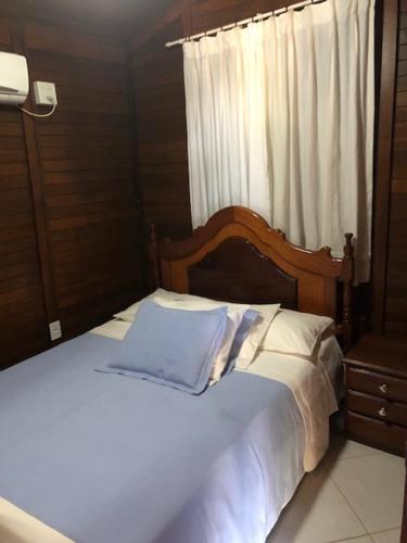 uma cama branca com uma cabeceira em madeira e uma janela em Pousada Jardim da Chapada em Chapada dos Guimarães