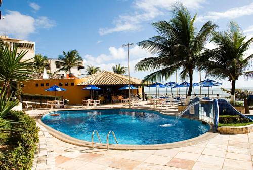 una piscina con sillas y sombrillas en un complejo en Happy Hotel Praia Azul, en Natal
