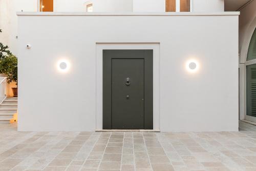 a black door in a white wall with two lights at Dimora Clementina in Putignano