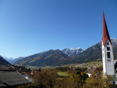 a church with a steeple with mountains in the background at Haus Driendl in Mieders