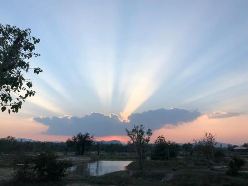 a sunset with a rainbow in the sky over a river at I love phants Lodge in Ban Huai Thawai