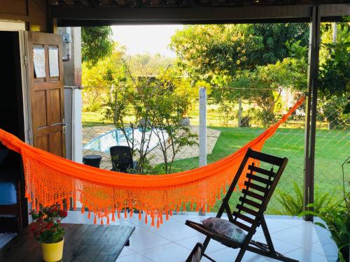an orange hammock on a porch with a chair at Pousada Jardim da Chapada in Chapada dos Guimarães