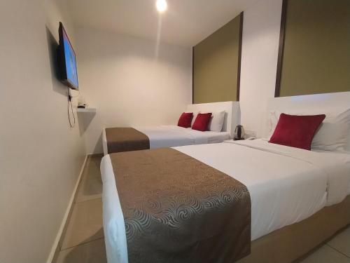 two beds in a hotel room with a flat screen tv at Crescendo Boutique Hotel in Nusajaya