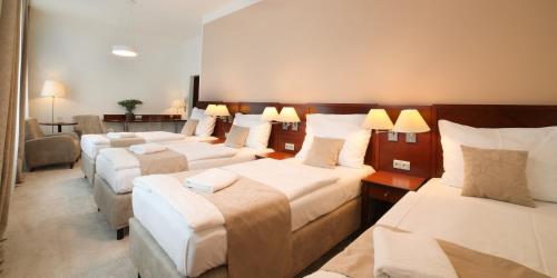 a hotel room with three beds and a couch at Hotel KOZÁK in Brno
