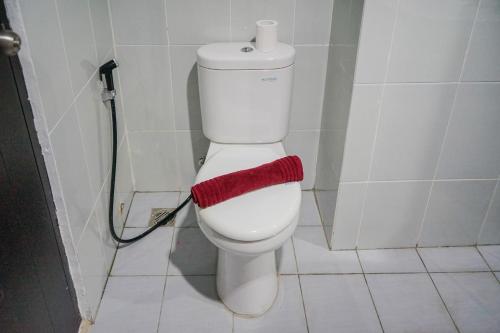 a bathroom with a toilet with a red towel on it at Modern and Tranquil 1BR @ Casa De Parco Apartment By Travelio in Tangerang