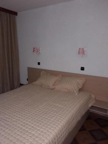 a bed in a bedroom with two lights on the wall at Къща за гости Динас in Zmeitsa