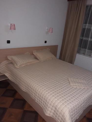 a bedroom with a bed with white sheets and a window at Къща за гости Динас in Zmeitsa