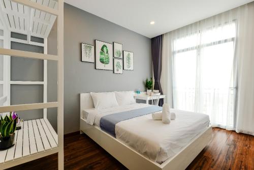 a bedroom with a white bed and a window at Cozrum Homes The Gallery Residence in Ho Chi Minh City