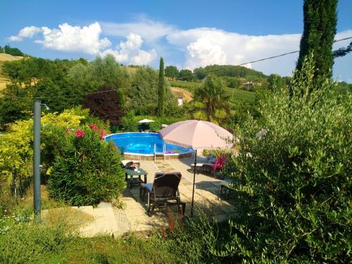 eine Terrasse mit Stühlen und einem Sonnenschirm neben einem Pool in der Unterkunft La Pietra Rara B&B in Montone