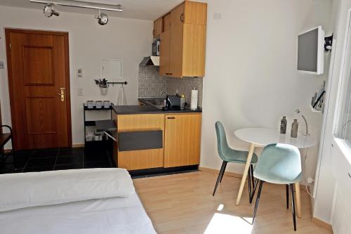 a small room with a kitchen and a table and chairs at Schick und freundlich, zentral, modernes Studio - C5 in St. Moritz