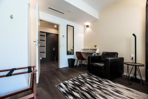 a living room with a black leather chair and a table at Blackhome Graz I contactless check-in in Graz