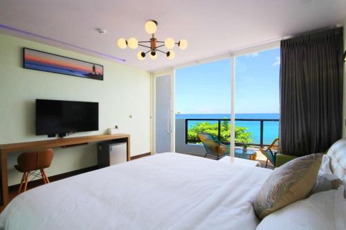1 dormitorio con 1 cama, TV y ventana en 墾丁 後灣 微風海岸海景民宿 en Checheng