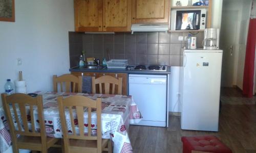 une cuisine avec une table et un réfrigérateur blanc dans l'établissement Vos vacances à Albiez Montrond, à Albiez-Montrond