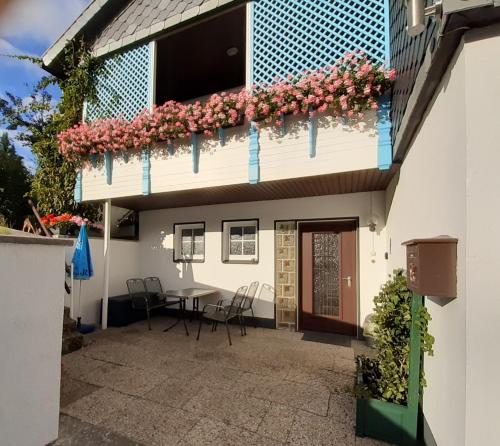 eine Terrasse eines Hauses mit einem Tisch und Blumen in der Unterkunft Ferienwohnung Rieger in Braunlage
