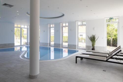 a swimming pool with a bench in a building at Hotel Upstalsboom Langeoog in Langeoog