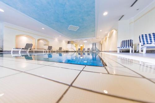 a swimming pool in a building with chairs and a swimming pool at Hotel Winzerhof in Termeno