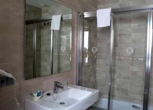 a bathroom with a sink and a shower with a mirror at Hotel 44 in Gijón