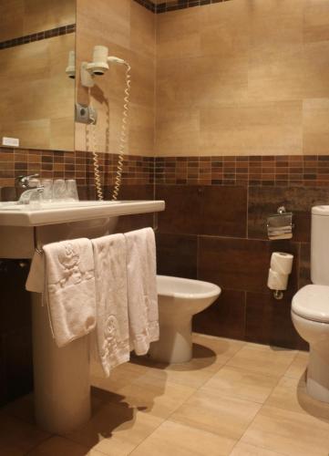 a bathroom with a sink and a toilet and towels at Hotel 44 in Gijón