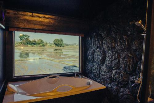 a bathroom with a window and a bath tub at Bantunglom Resort in Mae Rim