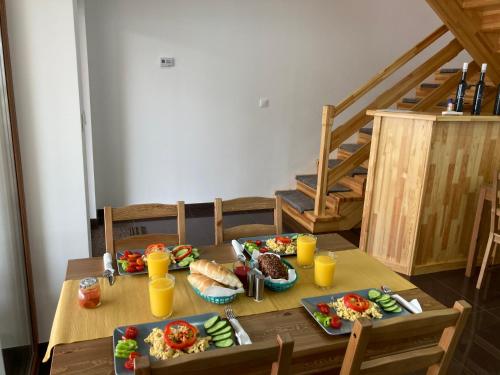a wooden table with plates of food and orange juice at Platán Panzió in Csongrád