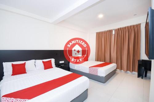 a hotel room with two beds with red and white at Kenyalang Suite in Miri