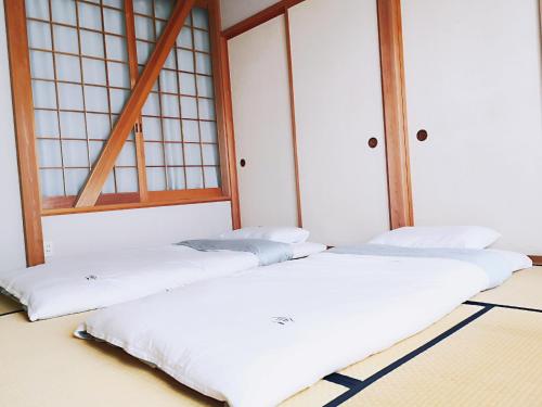 three white beds in a room with windows at 安野月江苑 Anno Gekkouen FUJI in Fujiyoshida