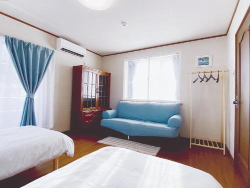 a bedroom with a blue couch and a window at 安野月江苑 Anno Gekkouen FUJI in Fujiyoshida