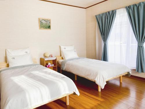 two beds in a room with a window at 安野月江苑 Anno Gekkouen FUJI in Fujiyoshida