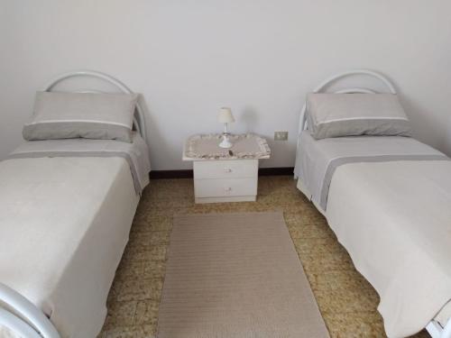 two beds in a room with a table between them at Casa via degli Ulivi 13 in Lozzo Atestino