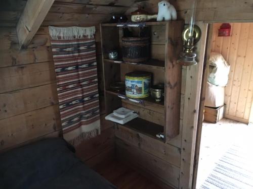 a room with a wooden wall with shelves in a cabin at Josygaard in Austefjorden