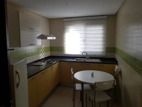 kuchnia ze stołem, umywalką i oknem w obiekcie Andalucia appart hoteL w mieście Bizerta