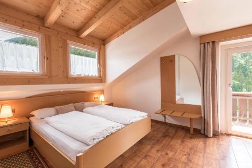 1 dormitorio con 1 cama en una habitación con ventanas en Villa Costa en Ortisei
