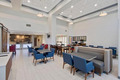 a dining room with tables and blue chairs at Holiday Inn Express Hotel & Suites Orlando - Apopka by IHG in Orlando