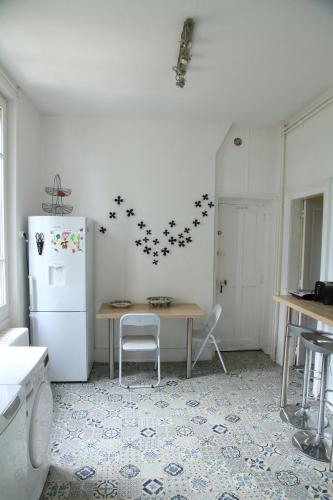 a kitchen with a table and a refrigerator with stars on the wall at Normandie 12 couchages in LʼAigle