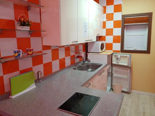 eine kleine Küche mit einer Spüle und einer Mikrowelle in der Unterkunft Rainbow Hill Pension in Namhae